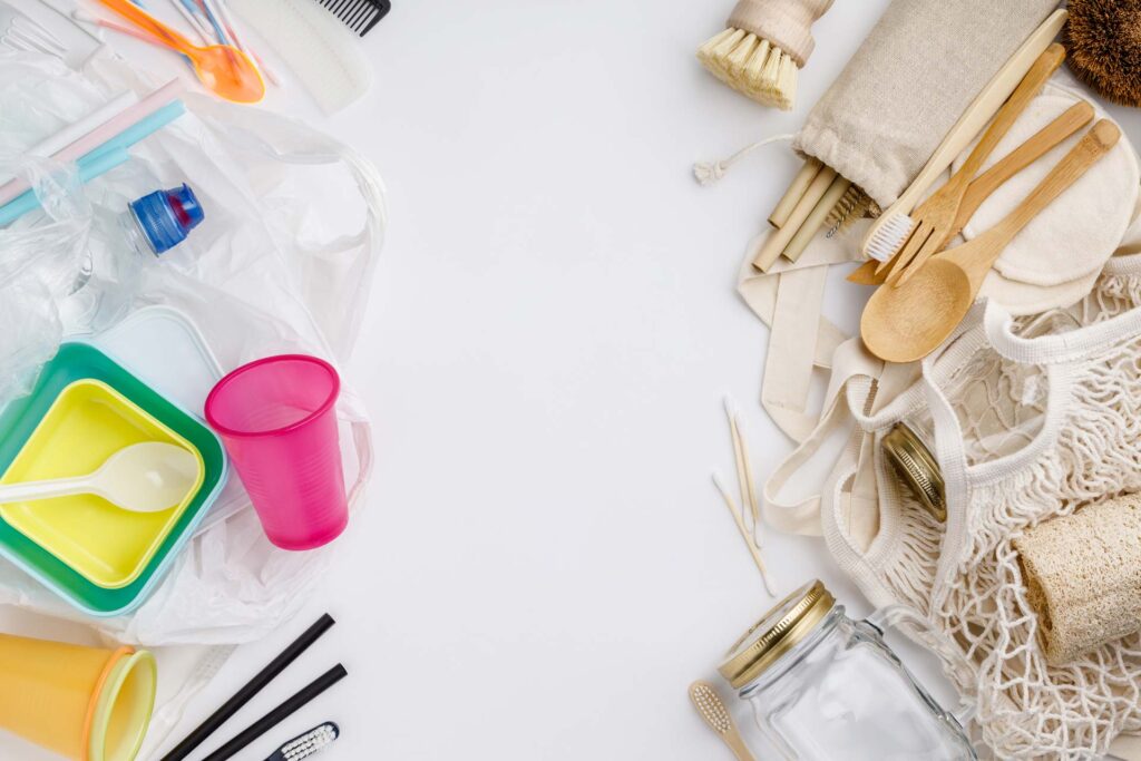 A flat lay of eco-friendly alternatives to plastic, including a stainless steel bottle, cloth bag, bamboo toothbrush, and compostable packaging, promoting sustainable lifestyle choices.